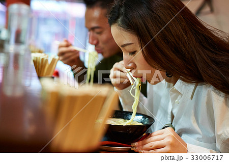 A man and a woman are eating noodles 33006717