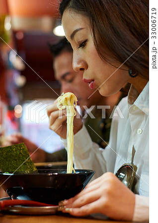the girl is eating noodles in the restaurant 33006719