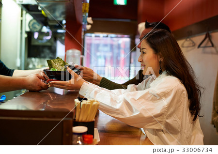a couple is getting a bowl of food from someone 33006734