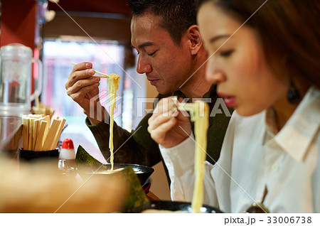 a couple is eating noodles together a couple is eating noodles together 33006738