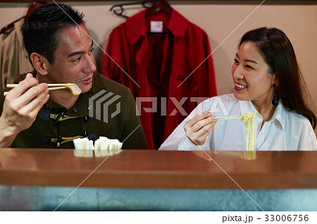 a couple is picking up food, looking at each other and smiling 33006756