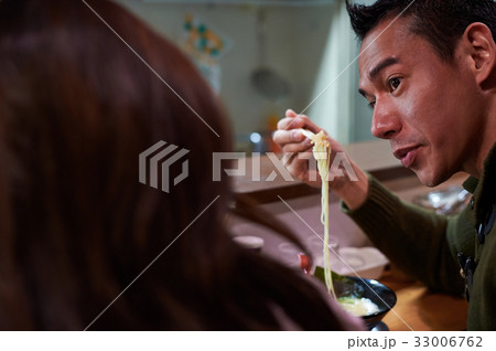 a man is picking up noodle by chopsticks and talking to a girl a man is picking up noodle by chopsticks and talking to a girl 33006762
