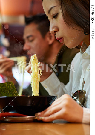 a girl is eating noodles next to a man 33006773
