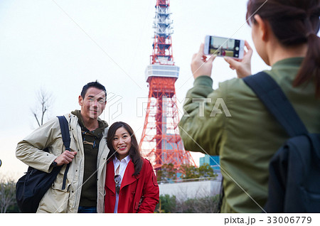 a girl is taking photo of couple near a tower 33006779