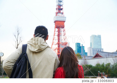 a photo of a couple standing and sightseeing near the tower 33006803