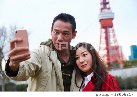 A beautiful couple takes selfie near Tokyo tower 33006817