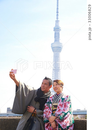 A couple in kimono is taking selfie near white tower 33006829