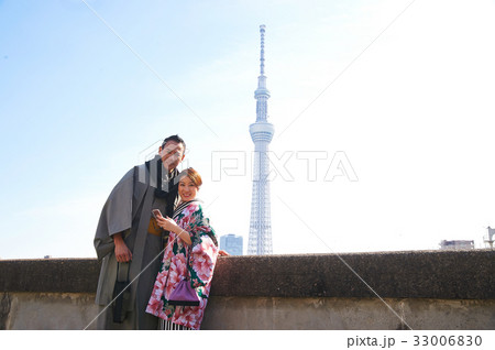 A photo of a happy couple in traditional Japanese kimono near white tower 33006830