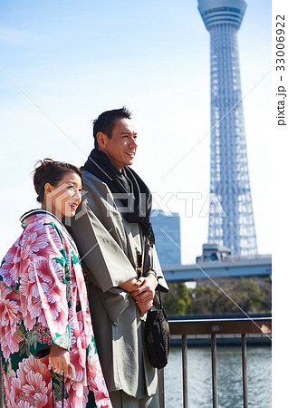 A woman and a man are standing and smiling near the tower in japan A woman and a man are standing and smiling near the tower in japan 33006922