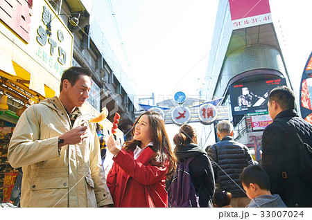 a photo of a couple holding food and smiling on a street a photo of a couple holding food and smiling on a street 33007024