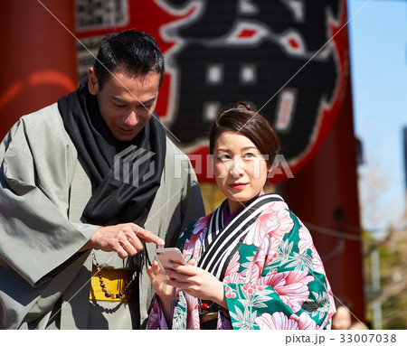 a man is looking at a phone while a woman is looking at something. 33007038