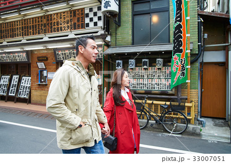 a photo of a couple holding hands and walking on a street. 33007051