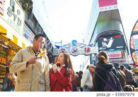 a couple is eating food on the crowded street a couple is eating food on the crowded street 33007079