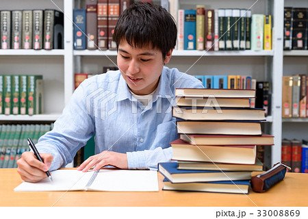 図書館で勉強する学生 山積みの本の写真素材