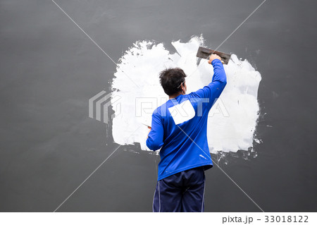 Builder plastering concrete wall with plaster 33018122