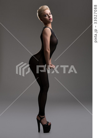 Sexy blonde in nylon overalls in profile in studio 33027088