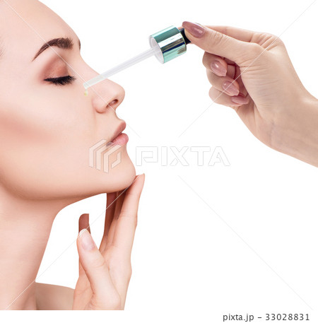 Cosmetic oil applying on face of young woman. Cosmetic oil applying on face of young woman. 33028831