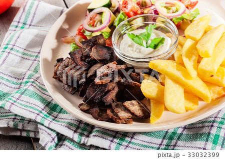 Grilled meat with French fries and vegetables Grilled meat with French fries and vegetables 33032399