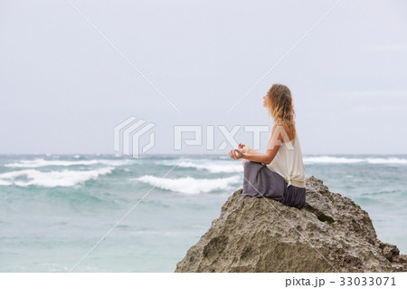 Girl sit at the seaside on the rock and meditating Girl sit at the seaside on the rock and meditating 33033071