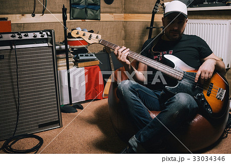 Bass guitarist with guitar in garage studio Bass guitarist with guitar in garage studio 33034346
