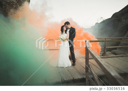 Wedding couple posing near rocks with colored 33036516