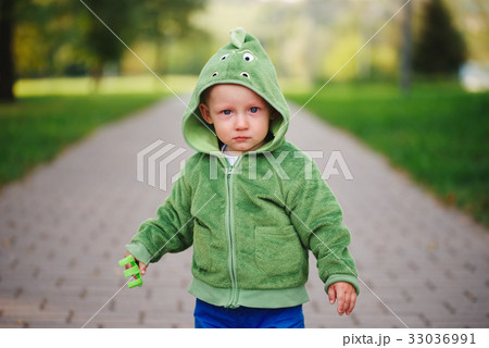 little unhappy boy with dinosaur costume 33036991
