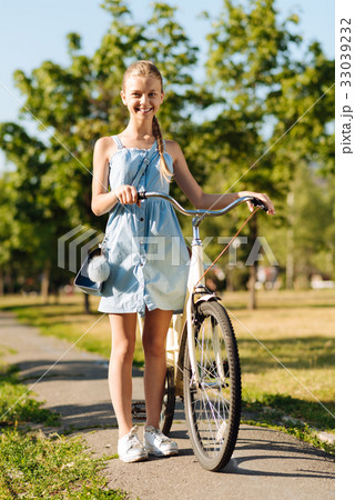 Cheerful little girl standing near her bicycle Cheerful little girl standing near her bicycle 33039232