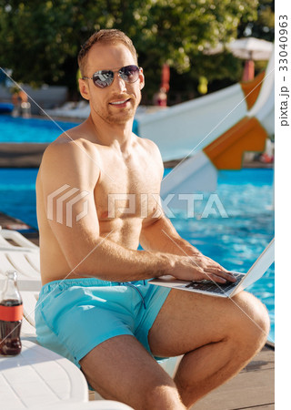 Athletic man sitting with laptop near swimming 33040963