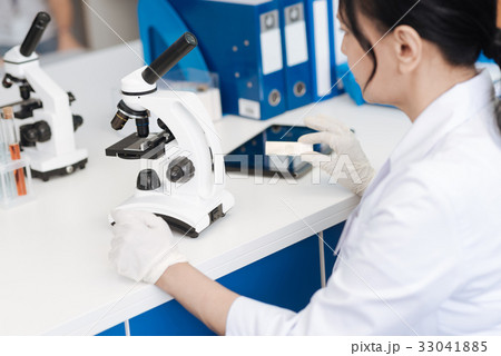 Nice intelligent woman working with a microscope 33041885