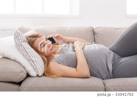 Smiling pregnant woman talking on her smartphone Smiling pregnant woman talking on her smartphone 33042702