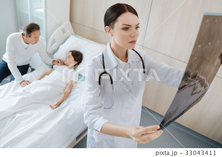 Serious thoughtful doctor looking at the X ray 33043411