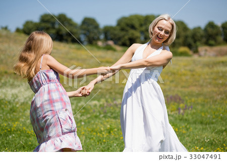 Mother and daughter dancing in a meadow. Mother and daughter dancing in a meadow. 33047491