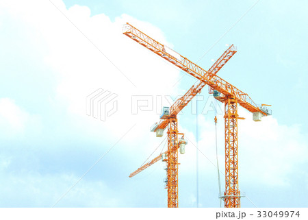 Two orange crane in cross on blue sky 33049974