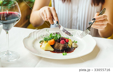 women eating beef steak with berry sauce 33055716