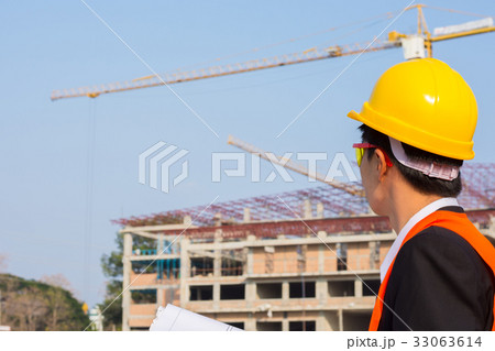 engineer wearing a orange shirt holding blueprint 33063614