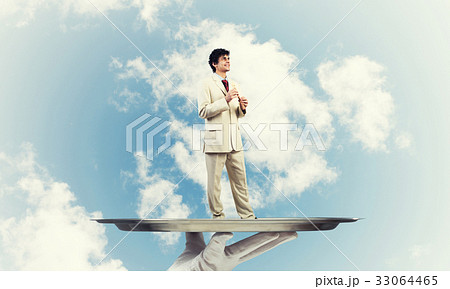 Businessman on metal tray playing fife against blue sky background Businessman on metal tray playing fife against blue sky background 33064465