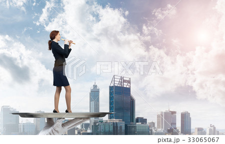 Attractive businesswoman on metal tray playing fife against cityscape background 33065067