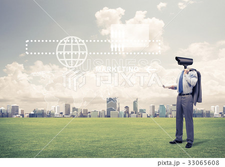 Camera headed man standing on green grass against modern citysca 33065608