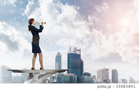 Attractive businesswoman on metal tray playing fife against cityscape background 33065841