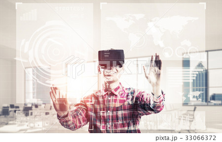 Young man in modern office interior experiencing virtual reality 33066372