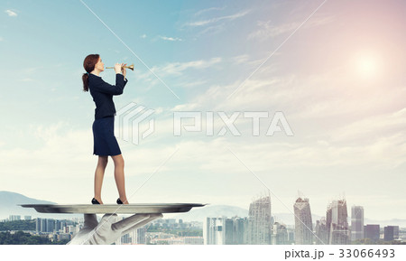 Attractive businesswoman on metal tray playing fife against cityscape background 33066493