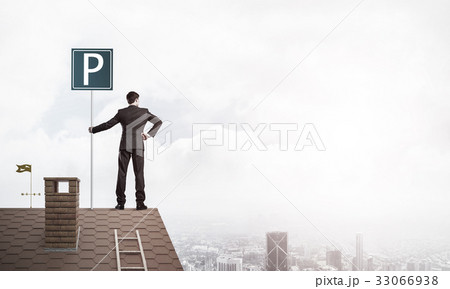 Young businessman with parking sign standing on brick roof. Mixe Young businessman with parking sign standing on brick roof. Mixe 33066938