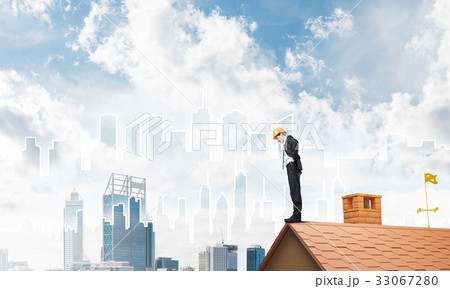 Engineer man standing on roof and looking down. Mixed media Engineer man standing on roof and looking down. Mixed media 33067280