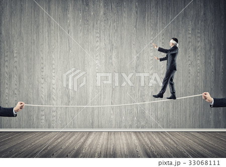 Business concept of risk support and assistance with man balancing on rope Business concept of risk support and assistance with man balancing on rope 33068111