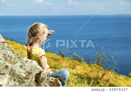 Nice blonde girl sitting on the shore of a lake 33074337