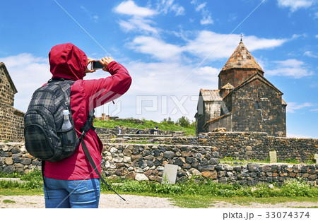 Hiker woman taking photo of ancient monastery 33074374