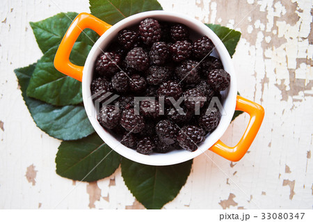 A full blackberry plate is on an old wooden 33080347