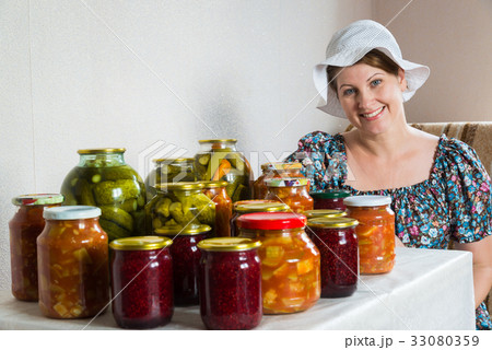 Housewife with canned vegetables and berries in Housewife with canned vegetables and berries in 33080359
