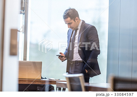 Businessman looking at smart phone in modern 33084597