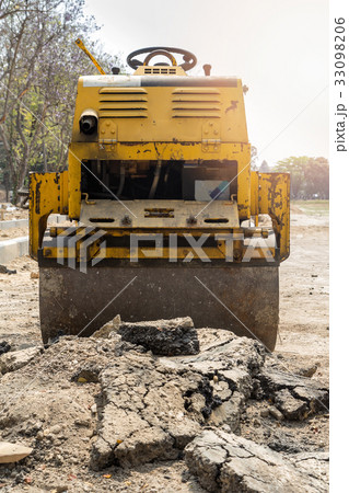 Yellow road roller in construction site 33098206